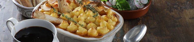 close up of shepherds pie with a jug of gravy on the side close up of shepherds pie with a jug of gravy on the side